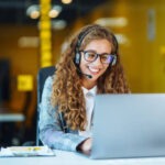 Call center agent with headset working on support hotline in modern office. Video conference.  Оnline training.